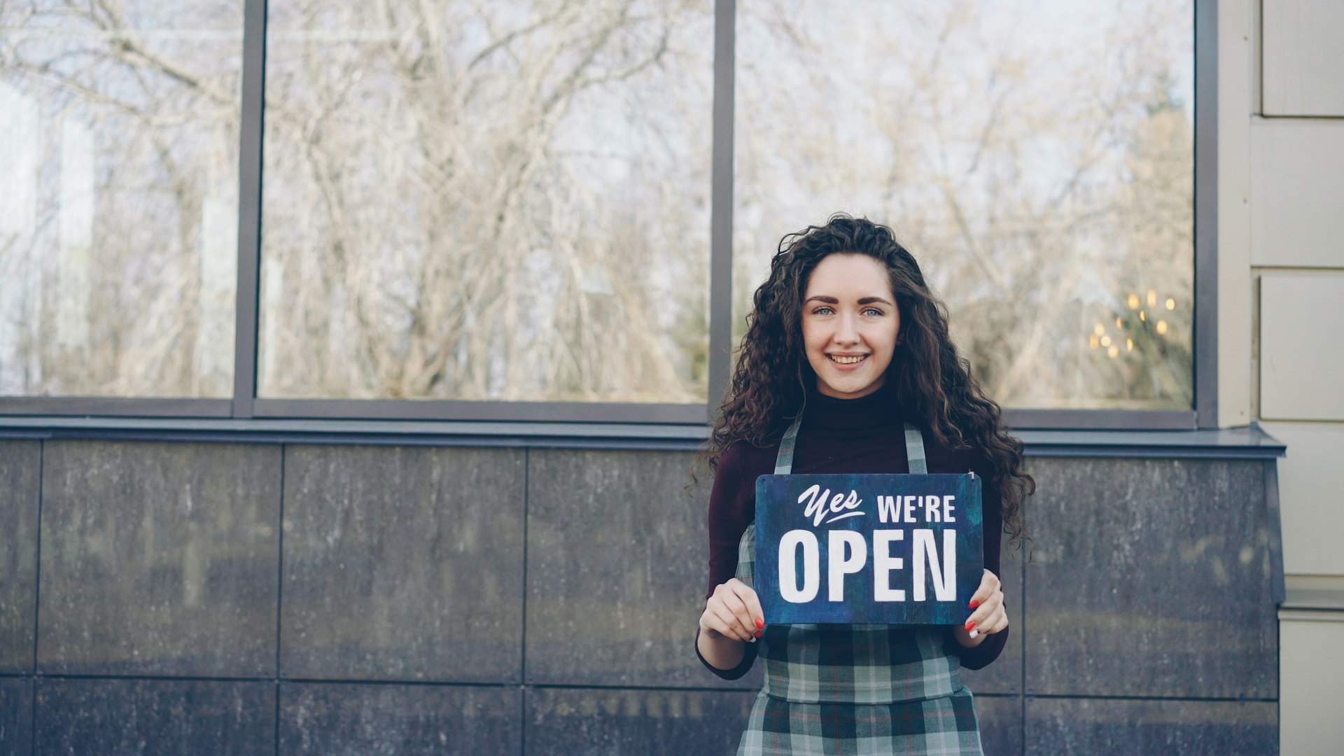 Shop owner holding an “Open” sign after learning how to apply WRT license for foreigners in Malaysia