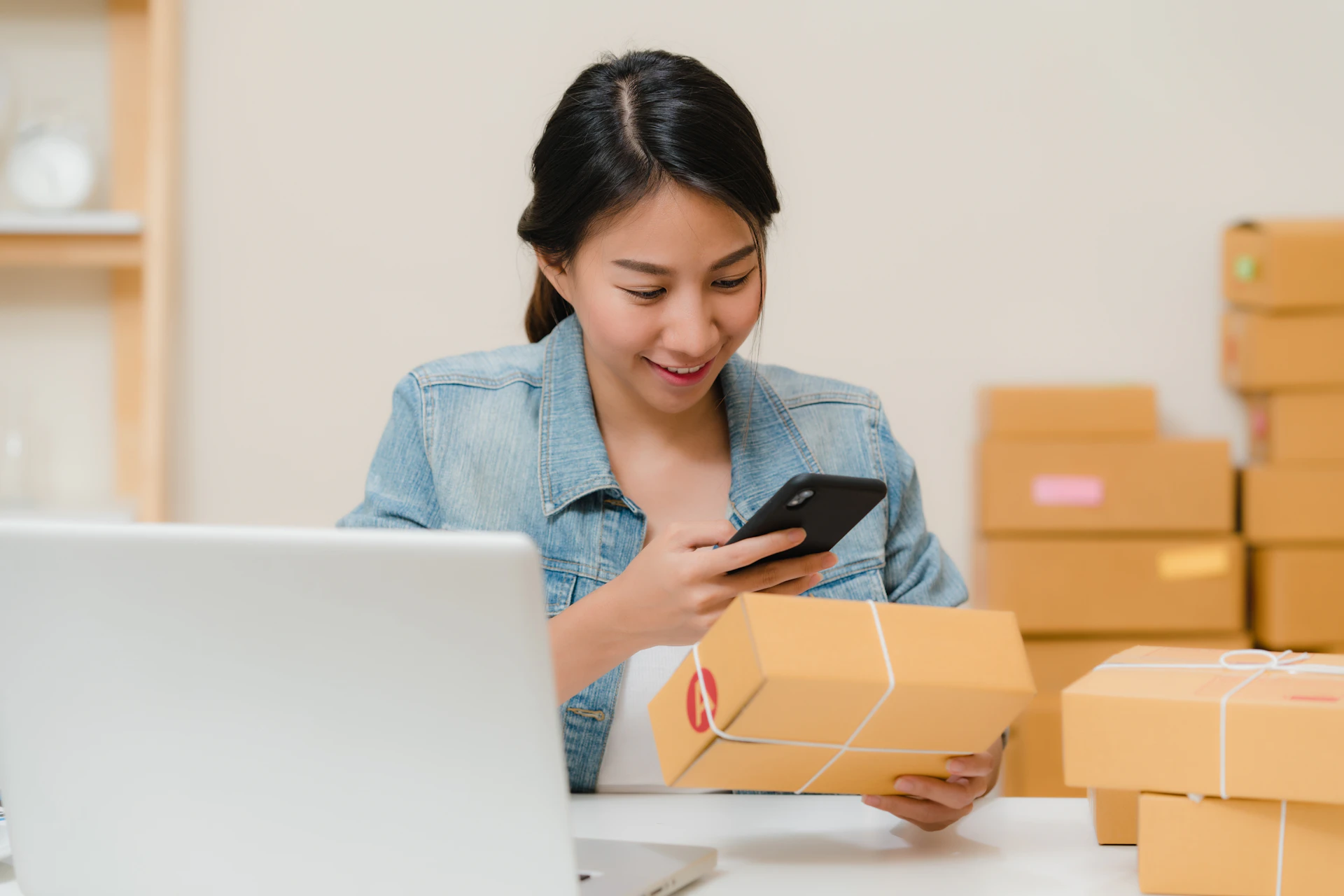 Online seller checking orders on her phone, covered by the e-commerce business license Malaysia rules